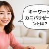 白を基調とした明るい室内で、観葉植物とウッド調の家具に囲まれながらノートパソコンを操作する、今どきの小顔であか抜けた雰囲気の主婦。自然なメイクを施し、笑顔でパソコン画面を見つめる姿。画像中央には吹き出しで『キーワードカニバリゼーションとは？』というピンク色のテキストが表示されている。